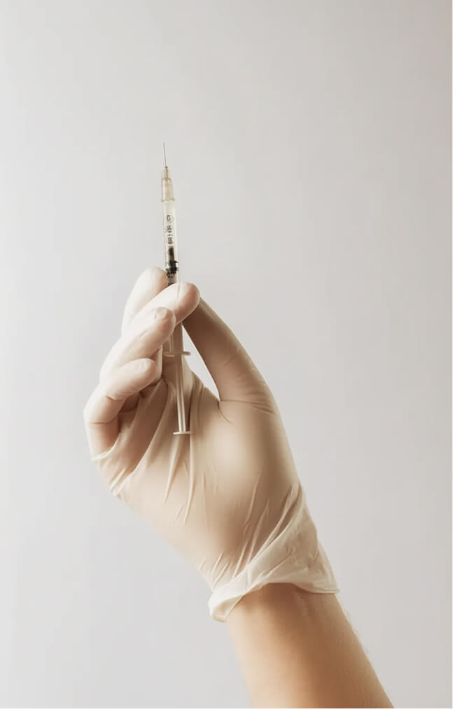 Gloved hand with medical syringe