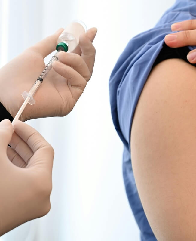 A healthcare professional preparing to administer an injection into a patient's arm