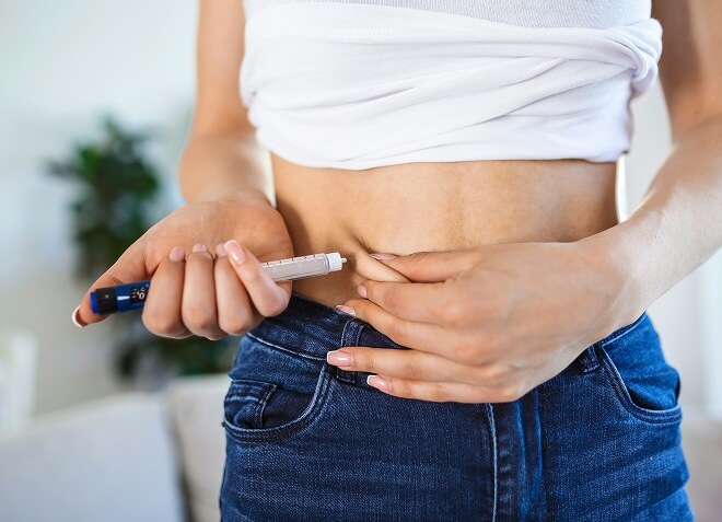 A person using an insulin pen in their abdomen