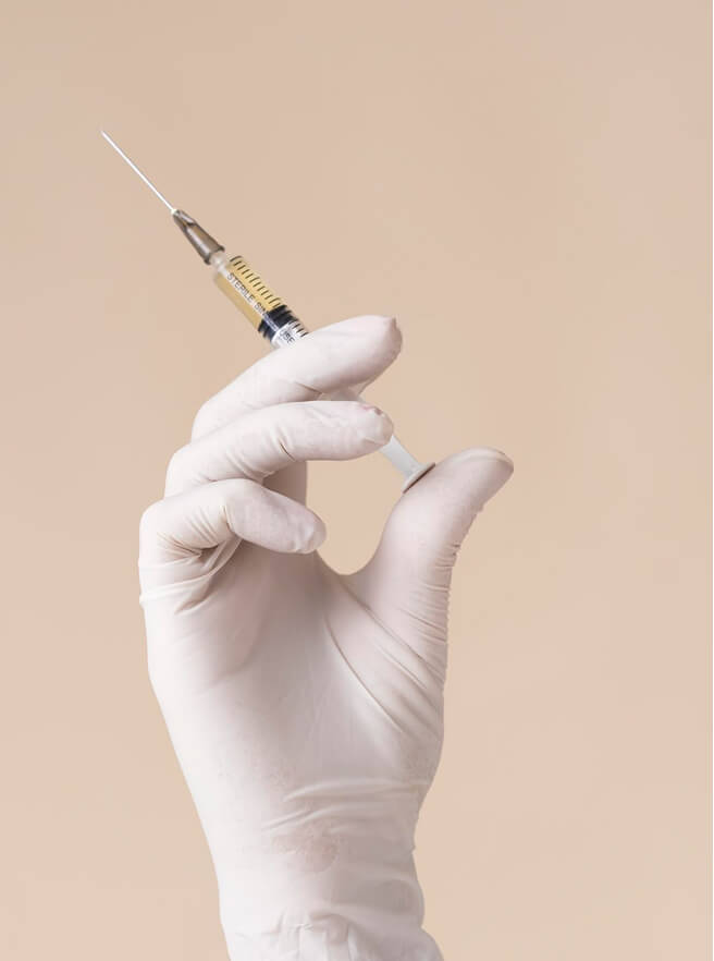 White glove holding a syringe
