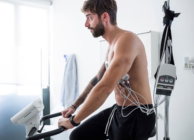 A man undergoing a cardiac stress test using a stationary exercise bike